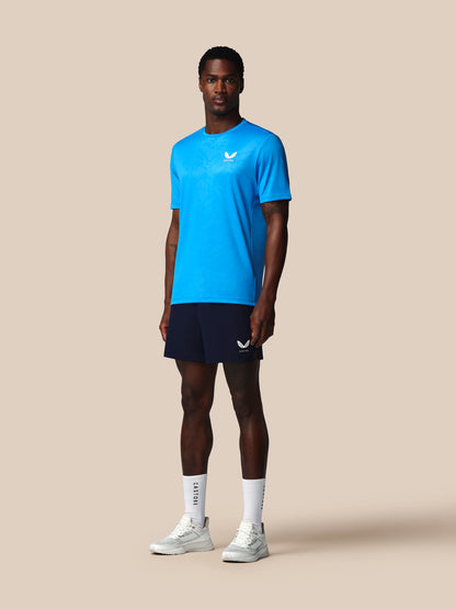 Man wearing a blue athletic shirt and black shorts on a beige background