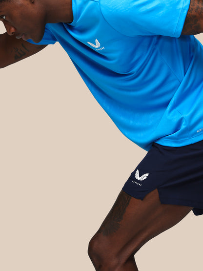 Person wearing a blue sports outfit with a logo on a beige background