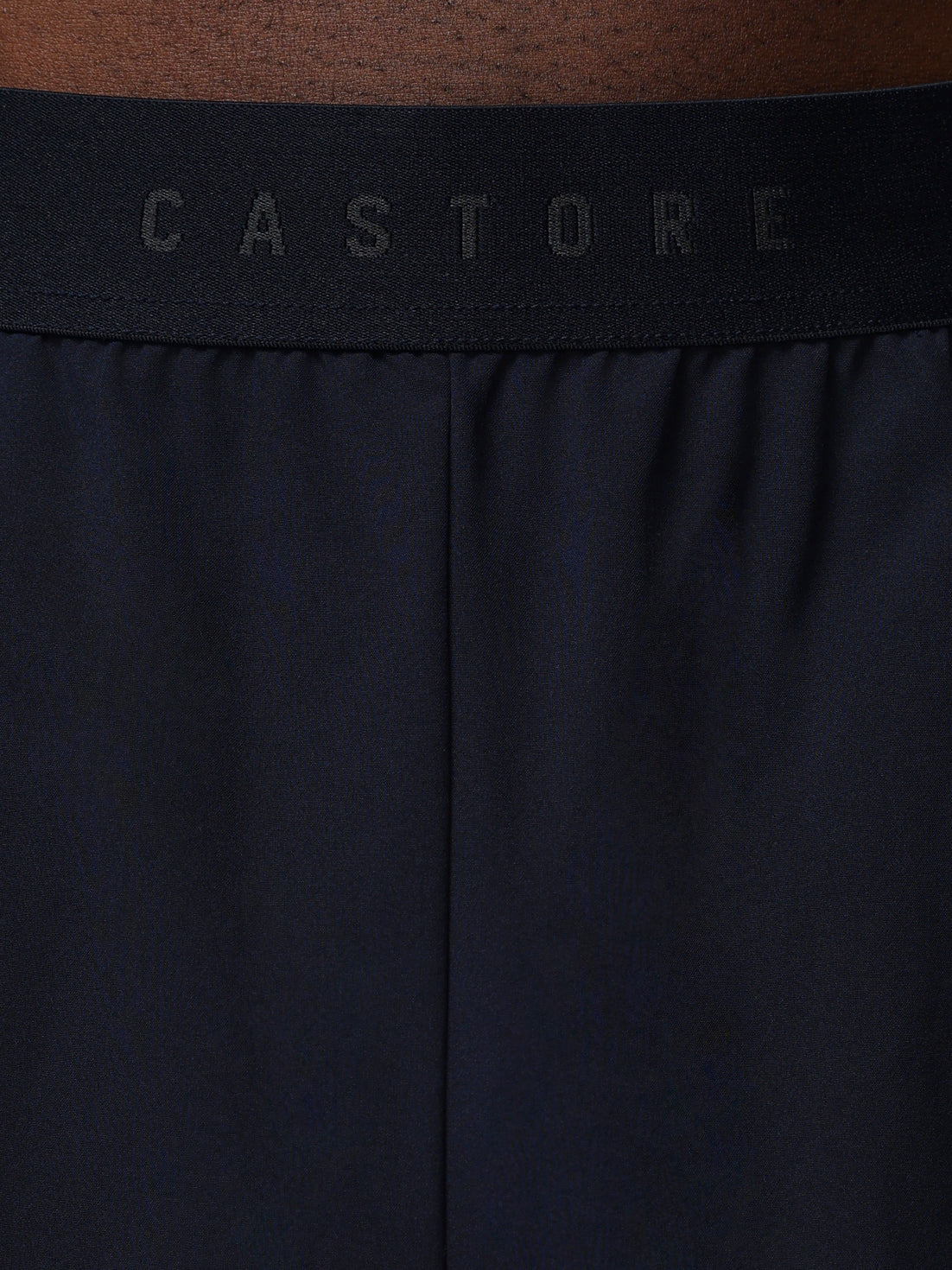 Close-up of a black waistband with 'CASTORE' branding on a brown background