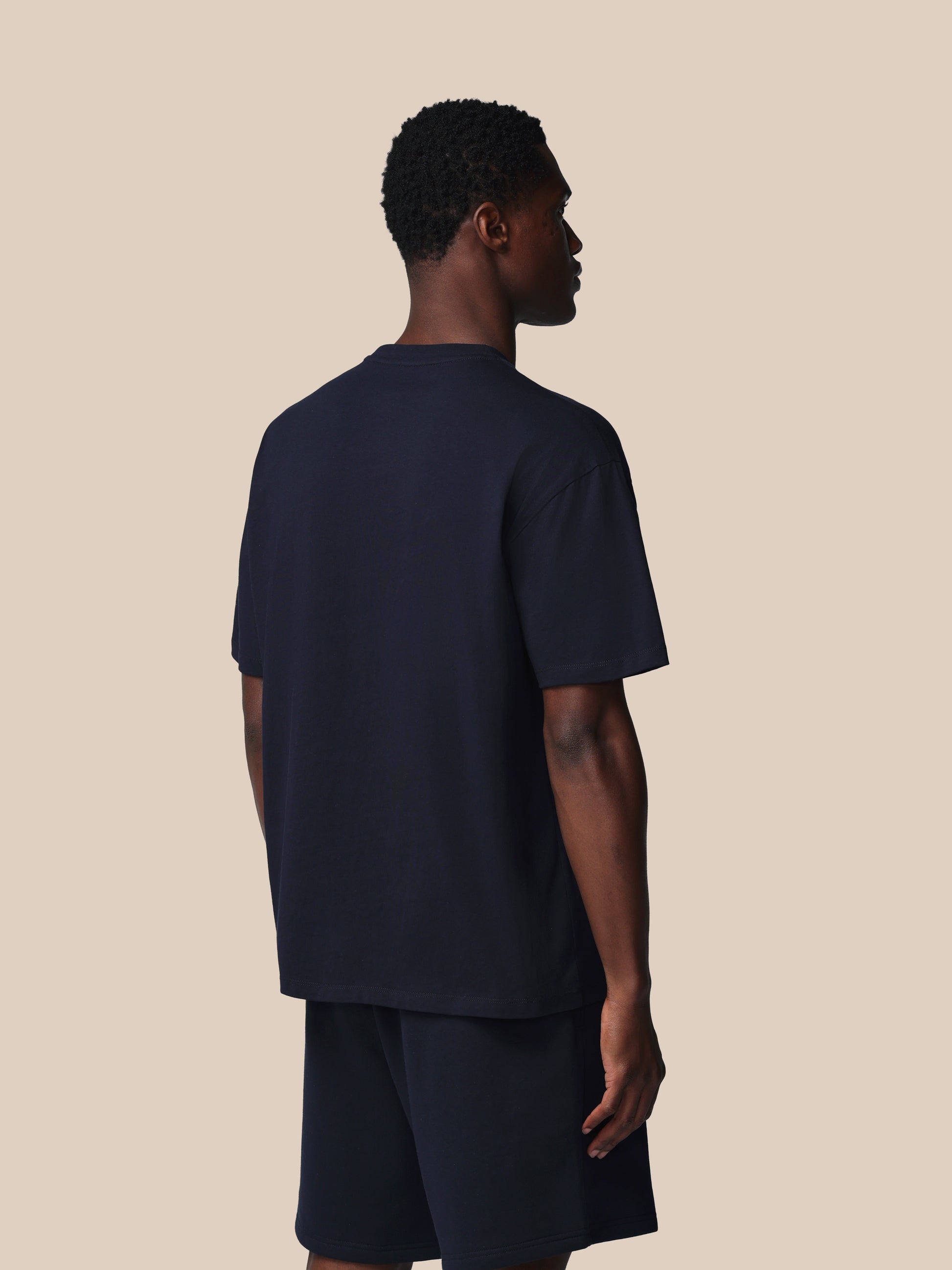 Person wearing a navy blue t-shirt and shorts set on a beige background