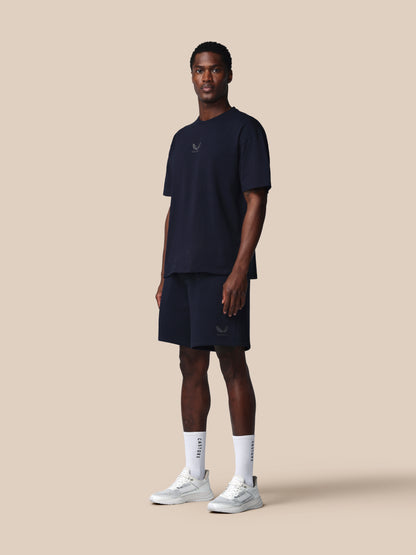 Man wearing a navy blue athletic outfit with white sneakers on a beige background