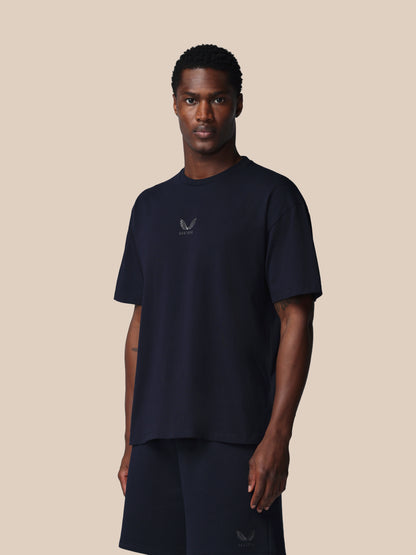 Man wearing a navy blue t-shirt with a logo on a beige background
