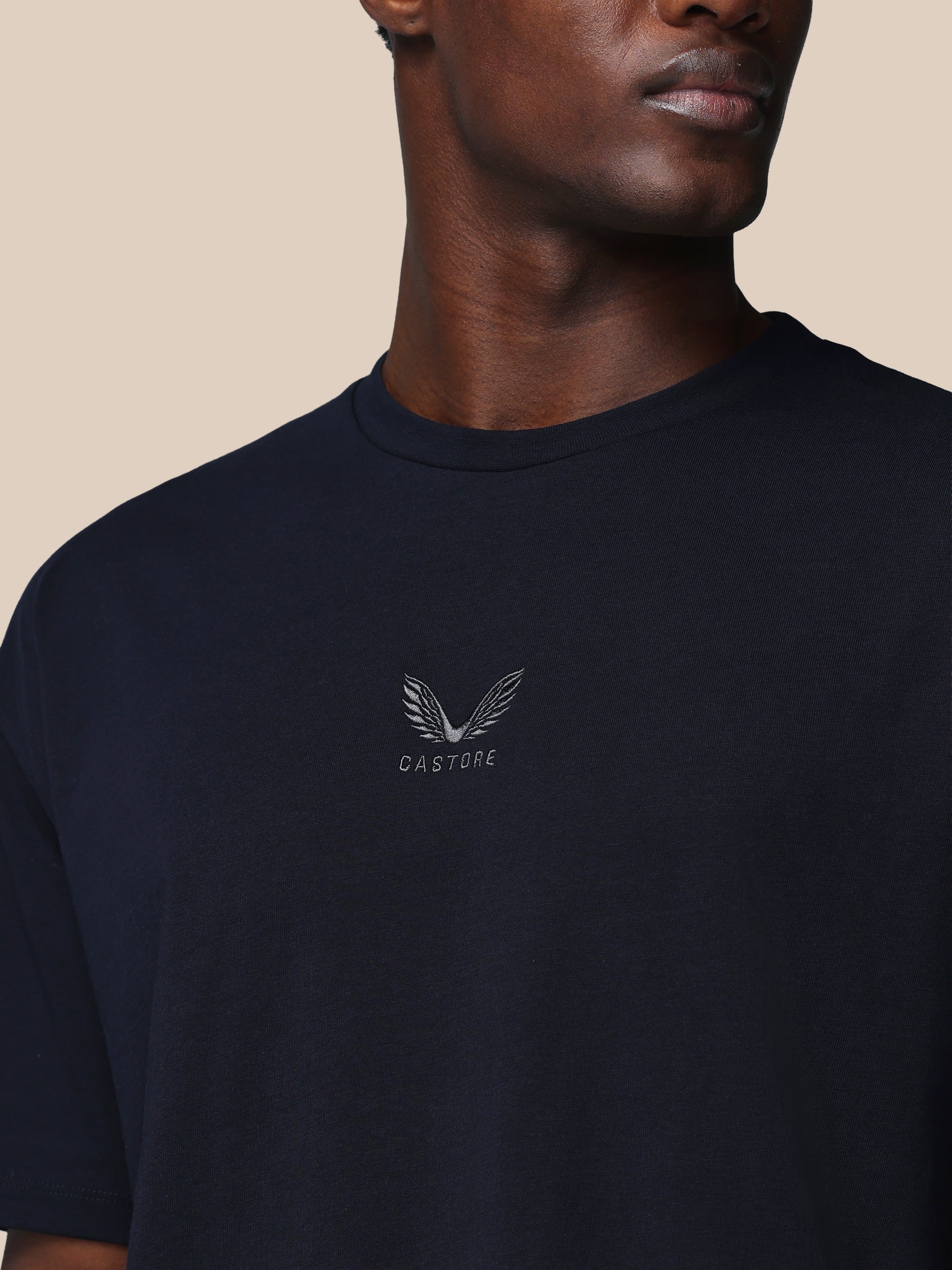 Man wearing a black t-shirt with a logo and text on a beige background