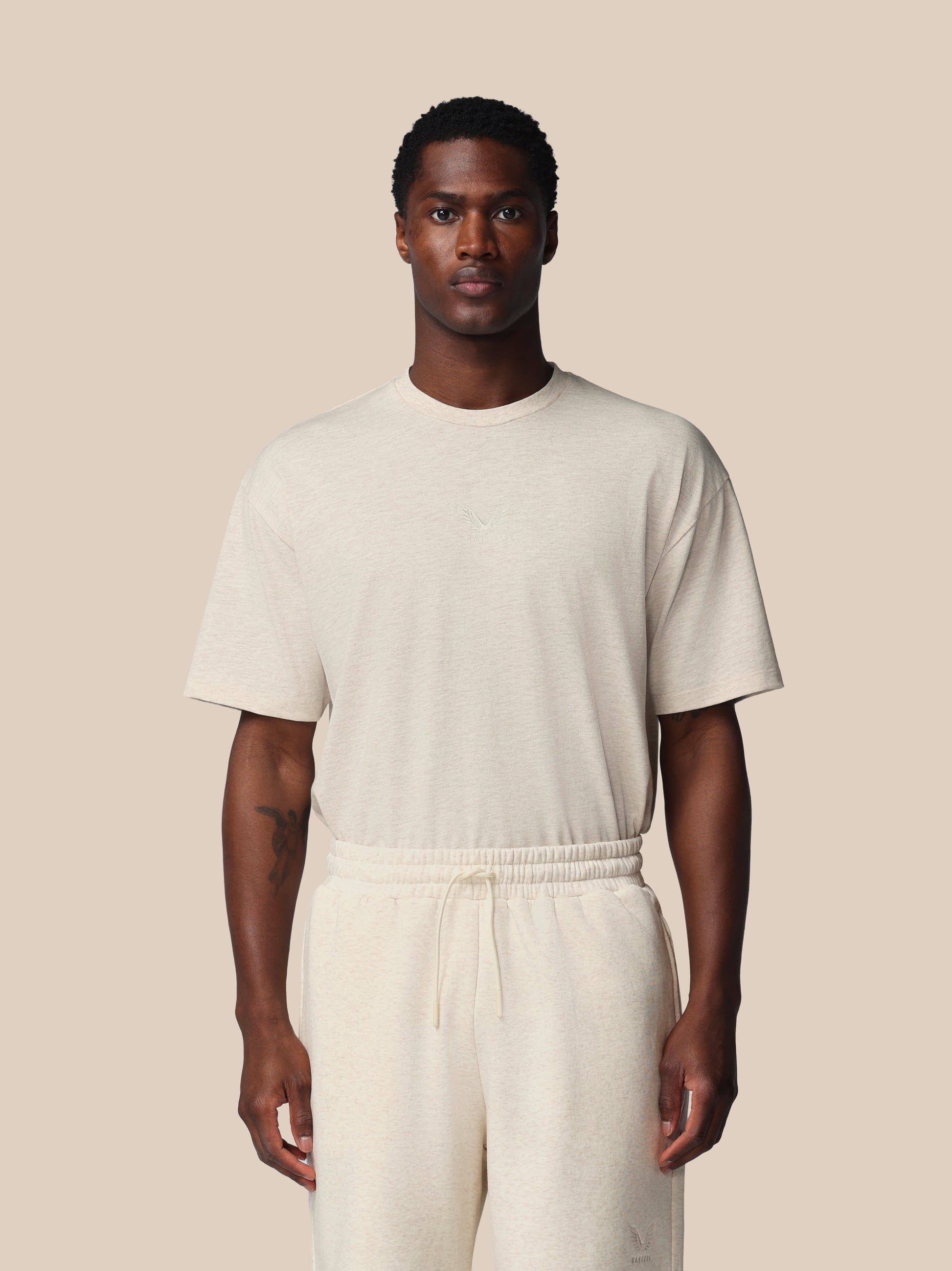 Man wearing a beige t-shirt and pants against a beige background