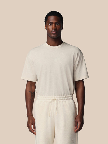 Man wearing a beige t-shirt and pants against a beige background