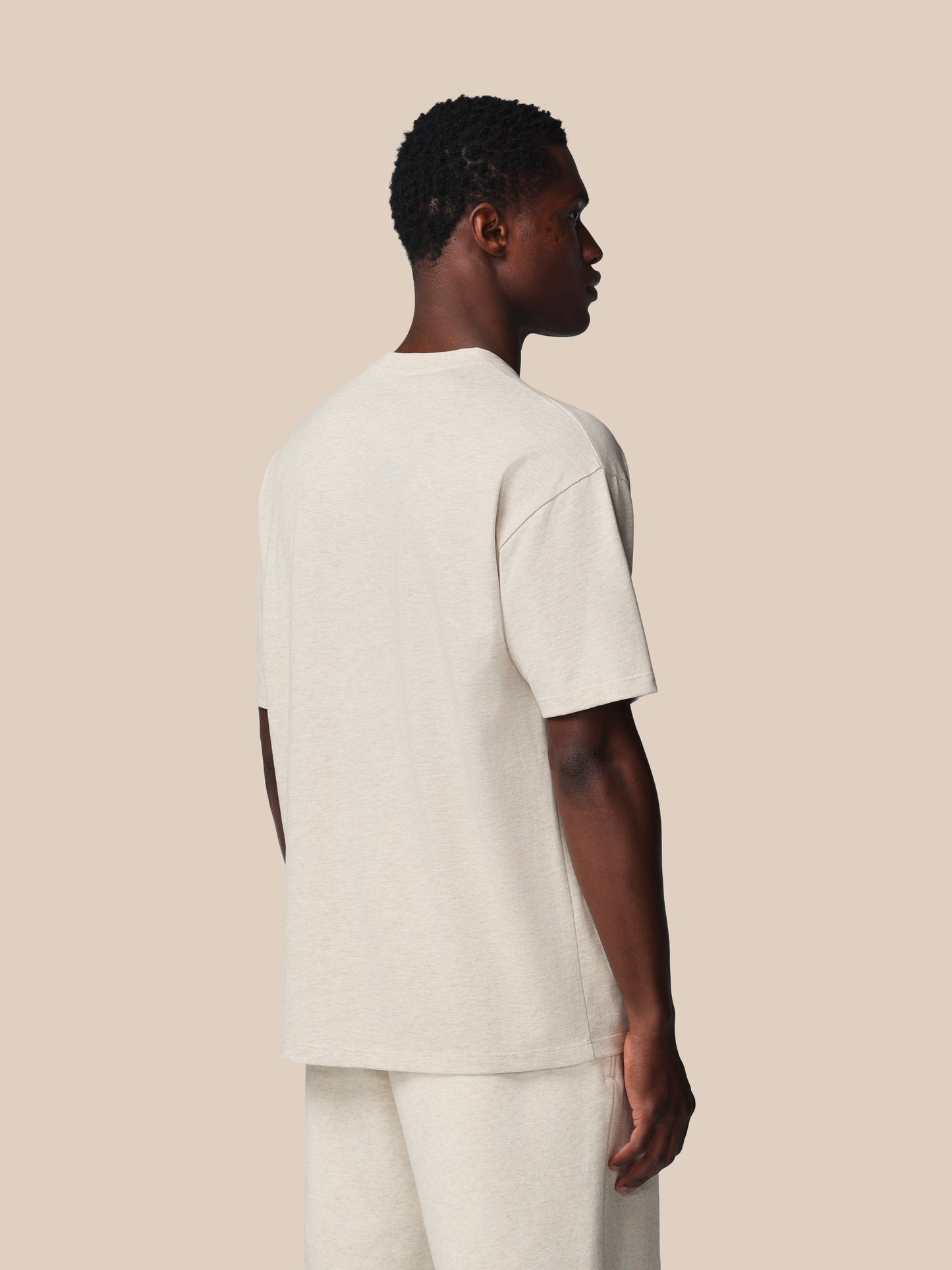 Person wearing a plain white t-shirt and pants on a beige background