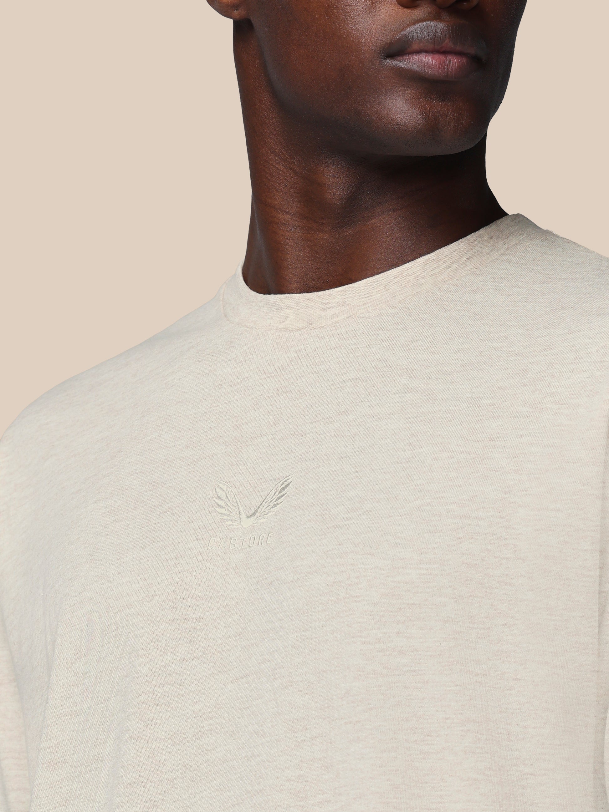 Close-up of a person wearing a light gray sweater with a subtle pattern on a beige background