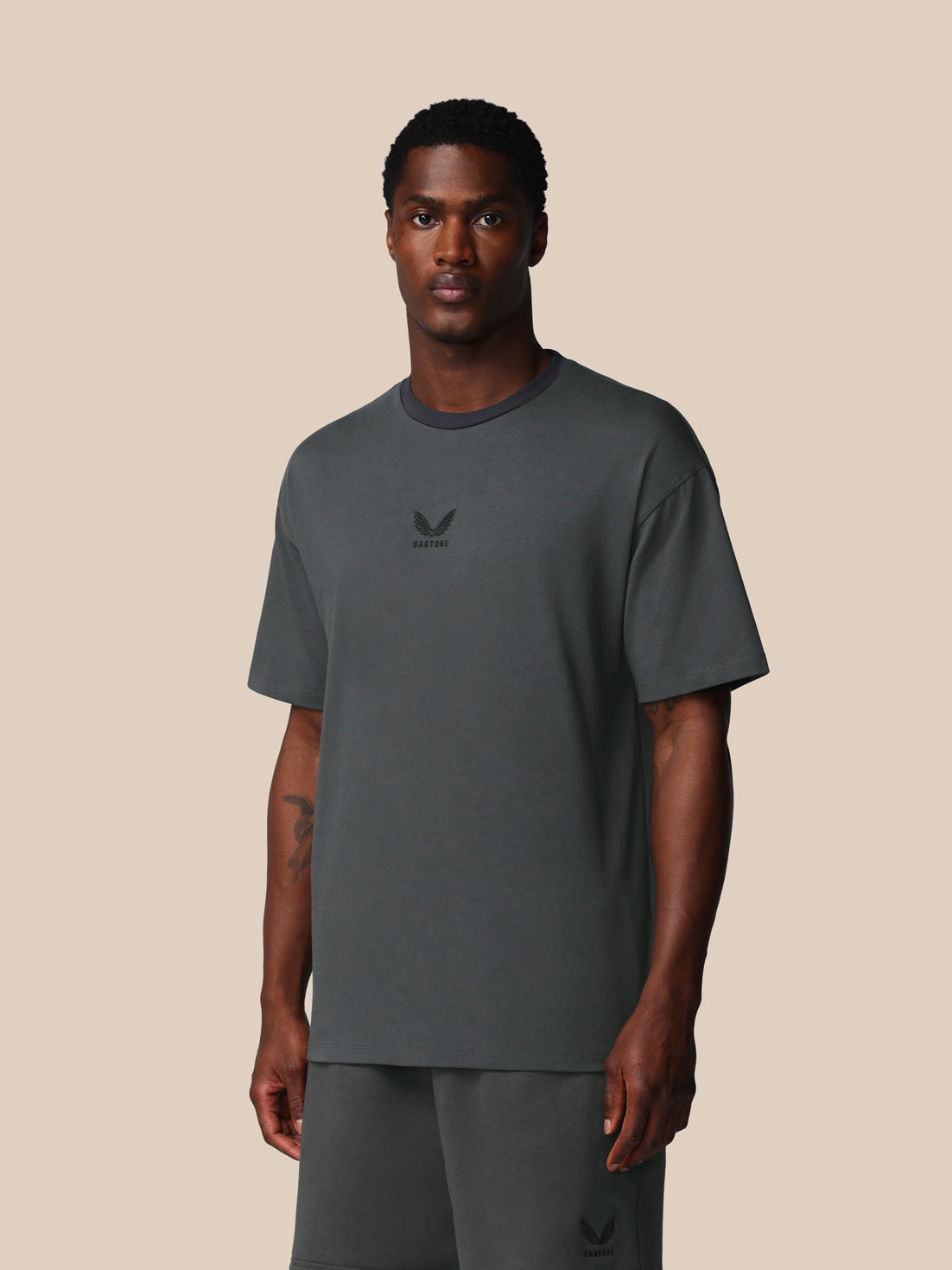 Man wearing a gray t-shirt with a logo on a beige background