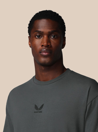 Man wearing a dark gray sweatshirt with a logo on a beige background