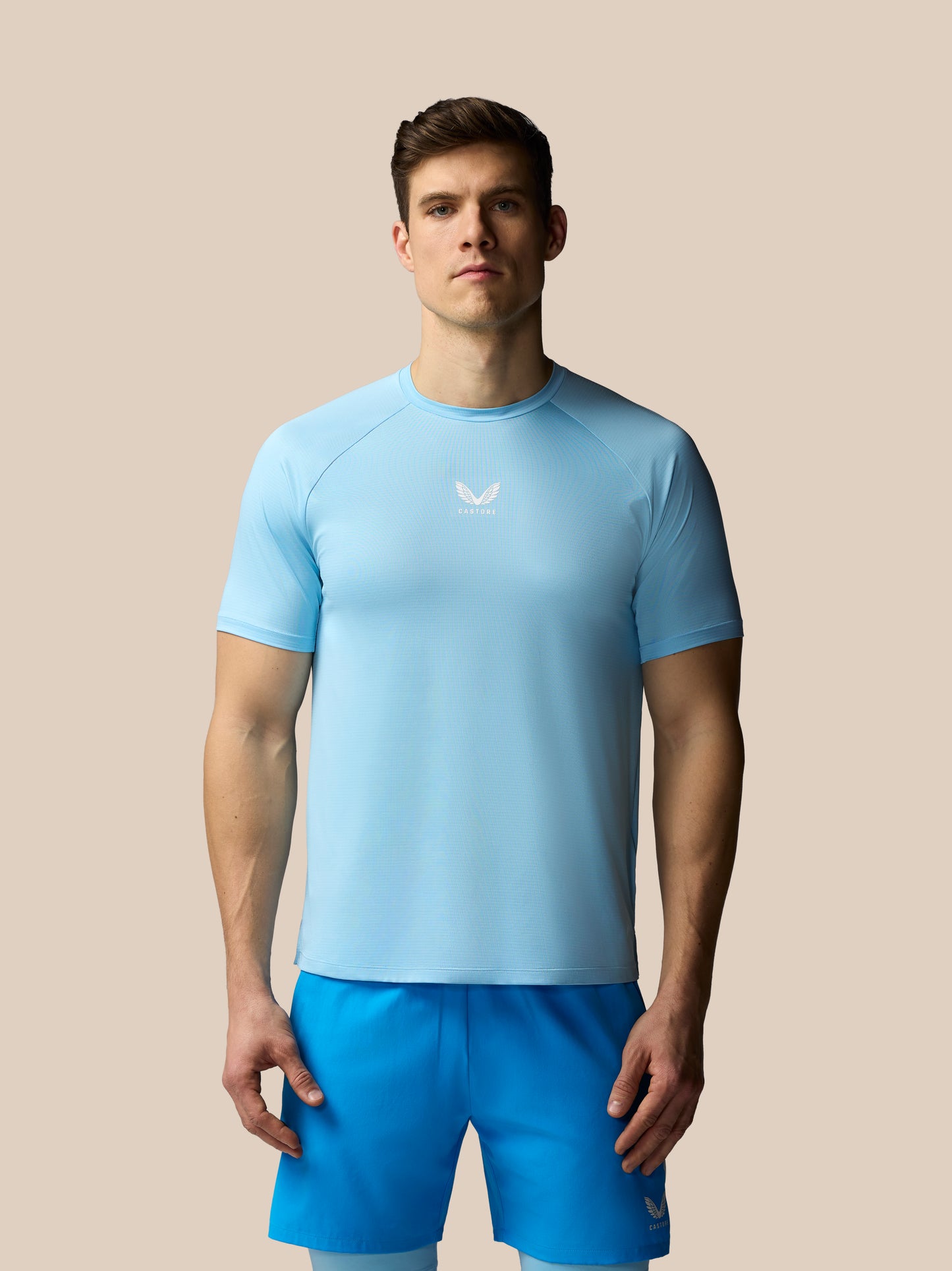 Man wearing a light blue athletic outfit with a logo on a beige background