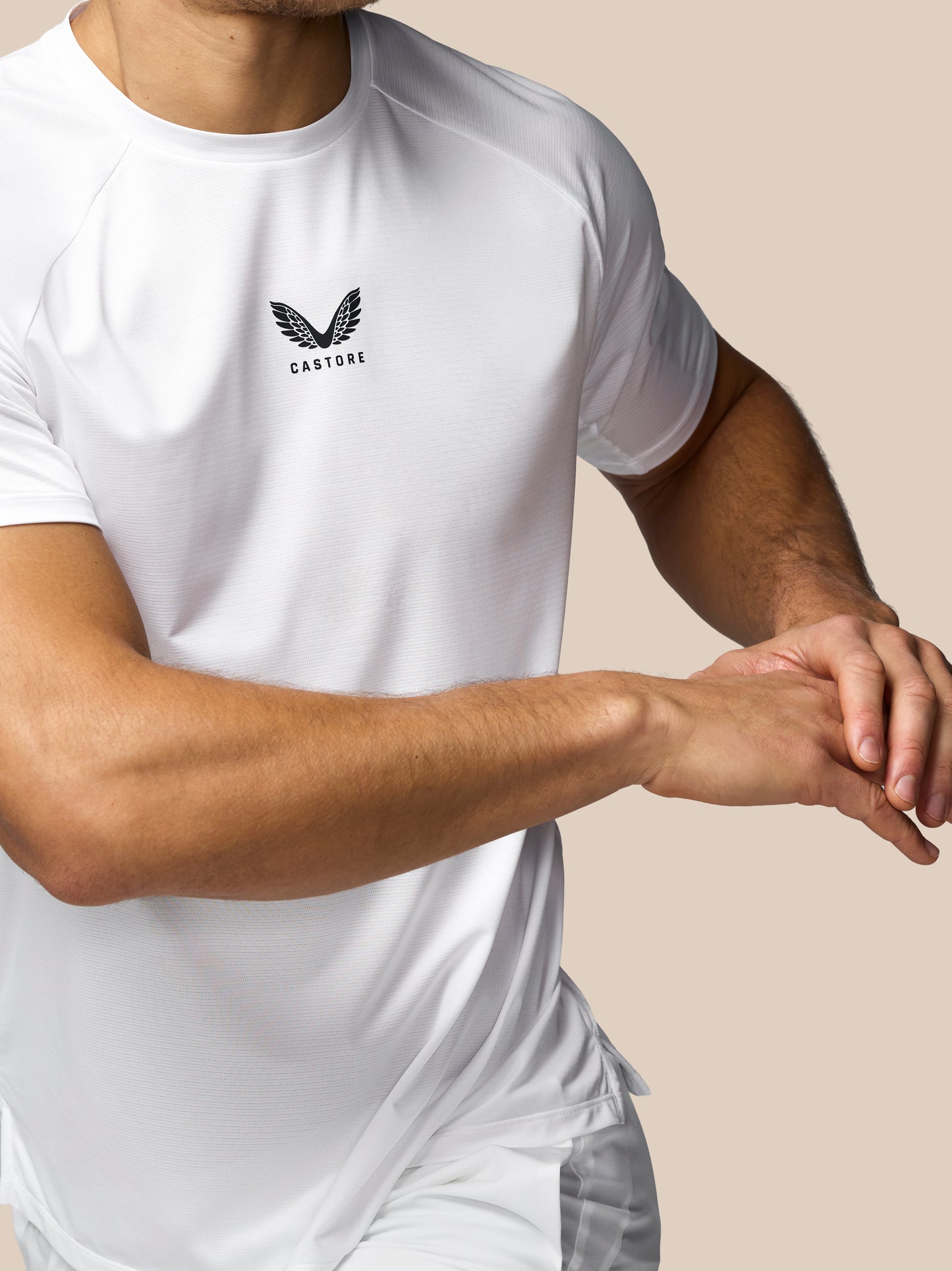 Person wearing a white t-shirt with a logo on a beige background