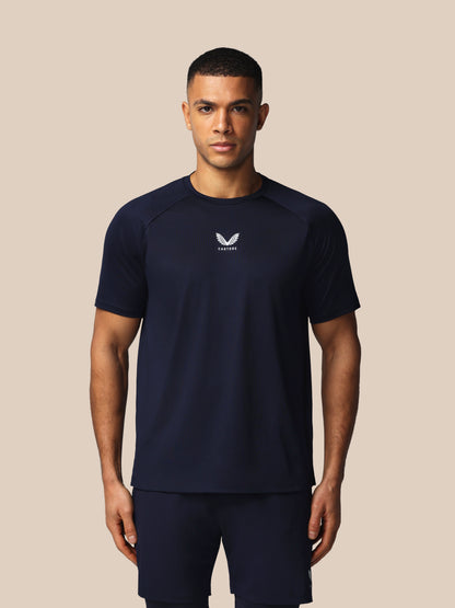 Man wearing a navy athletic outfit with a logo on a beige background