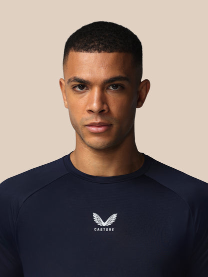 Man wearing a navy blue shirt with a logo on a beige background