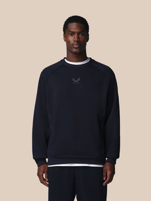 Man wearing a black sweatshirt with a logo on a beige background
