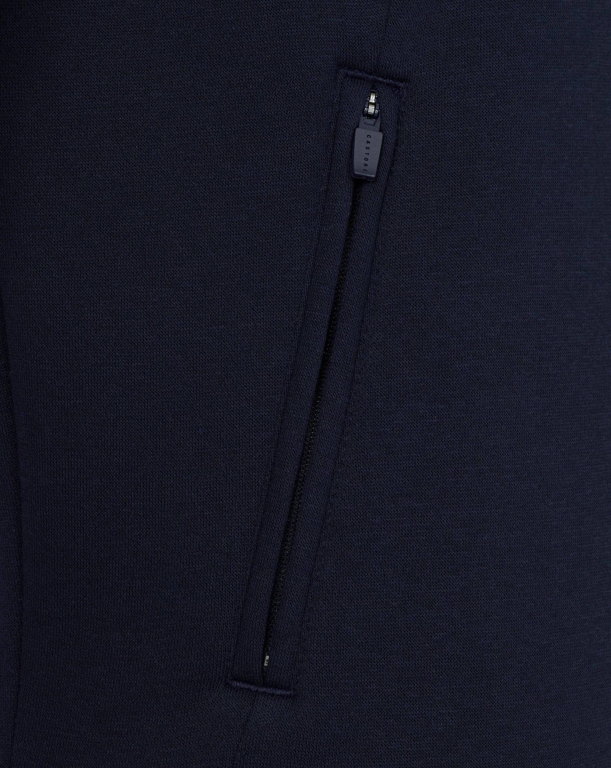 Close-up of a navy blue garment with a zipper on a matching background