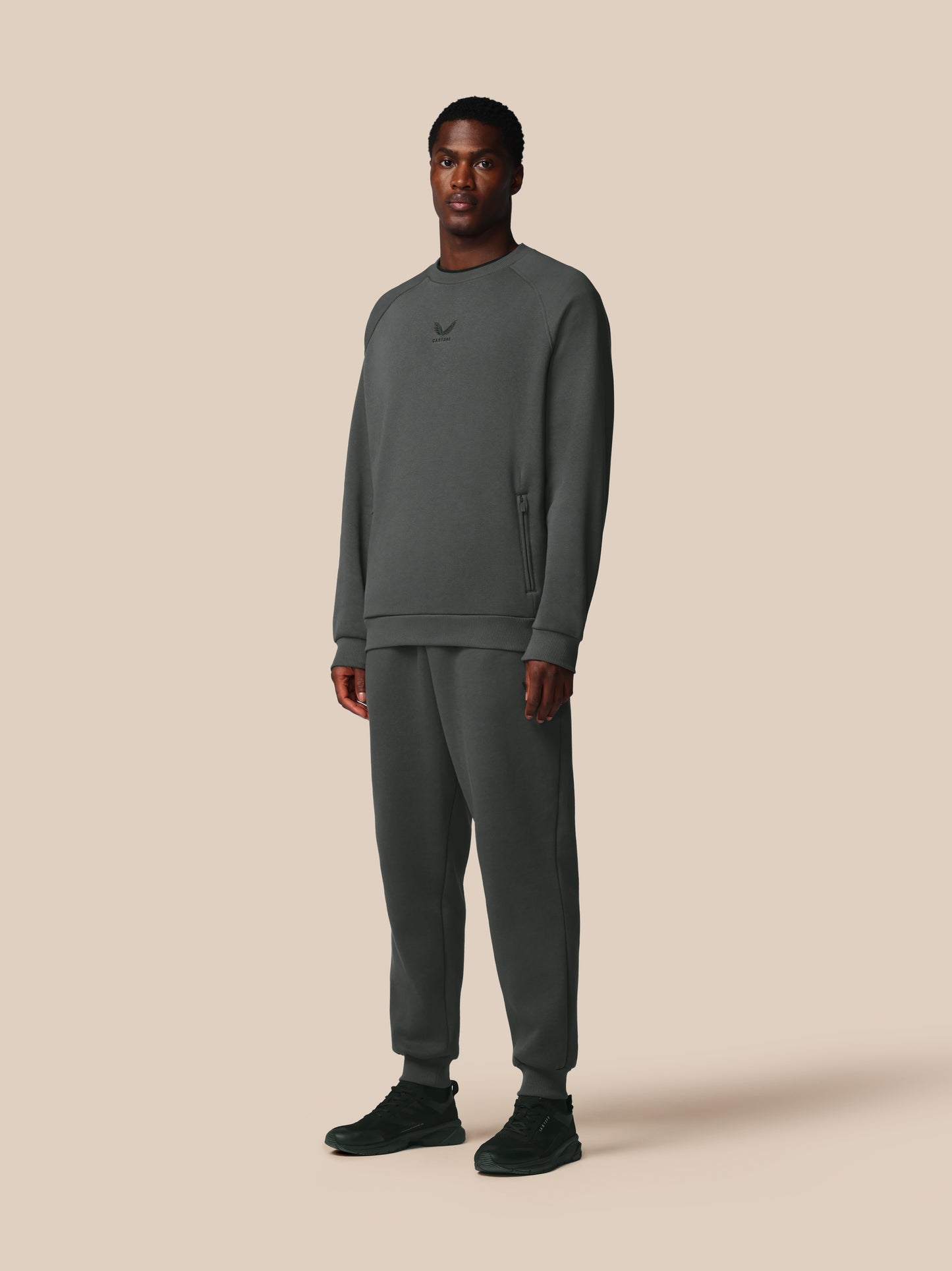 Man wearing a gray sweatshirt and pants on a beige background
