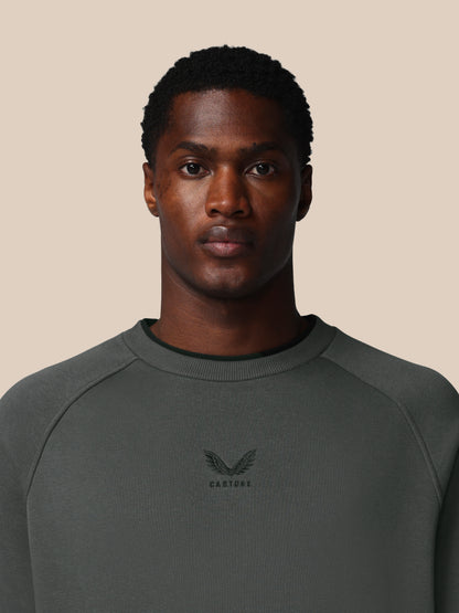 Man wearing a dark gray sweatshirt with a logo on a beige background