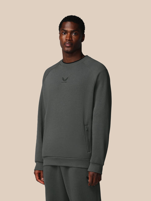 Man wearing a gray sweatshirt with a logo on a beige background