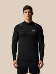 Man wearing a black long-sleeve athletic shirt with a logo on a beige background