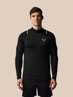 Man wearing a black long-sleeve athletic shirt with a logo on a beige background
