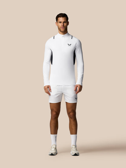 Man wearing a white athletic outfit with a logo on a beige background