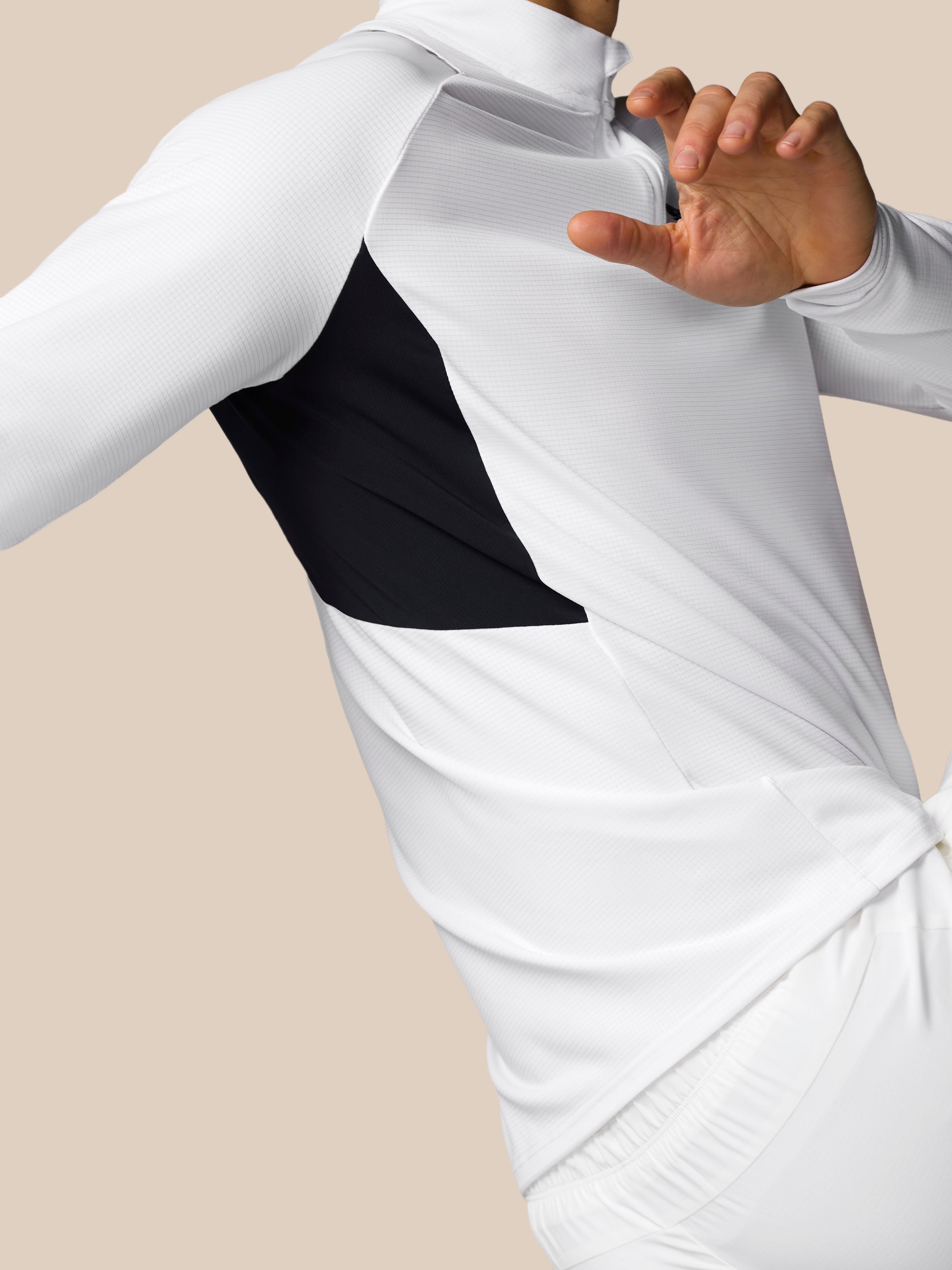 Close-up of a person wearing a white long-sleeve top with a black accent on a beige background