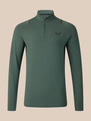 A dark green long-sleeve quarter-zip athletic top with a small wing logo on the left chest, displayed on a neutral beige background.