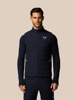 Man wearing a navy blue puffer vest with a brand logo on a beige background