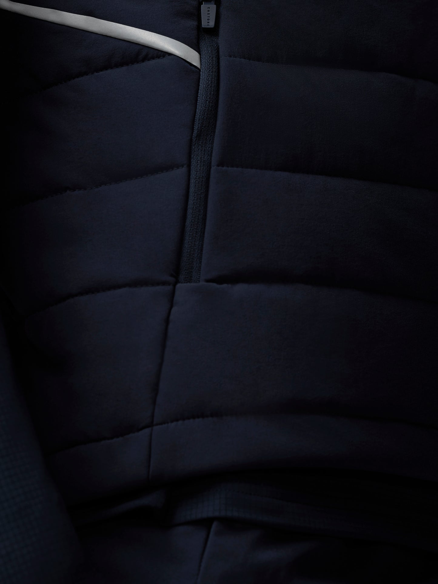 Close-up of a dark blue quilted jacket with a zipper.