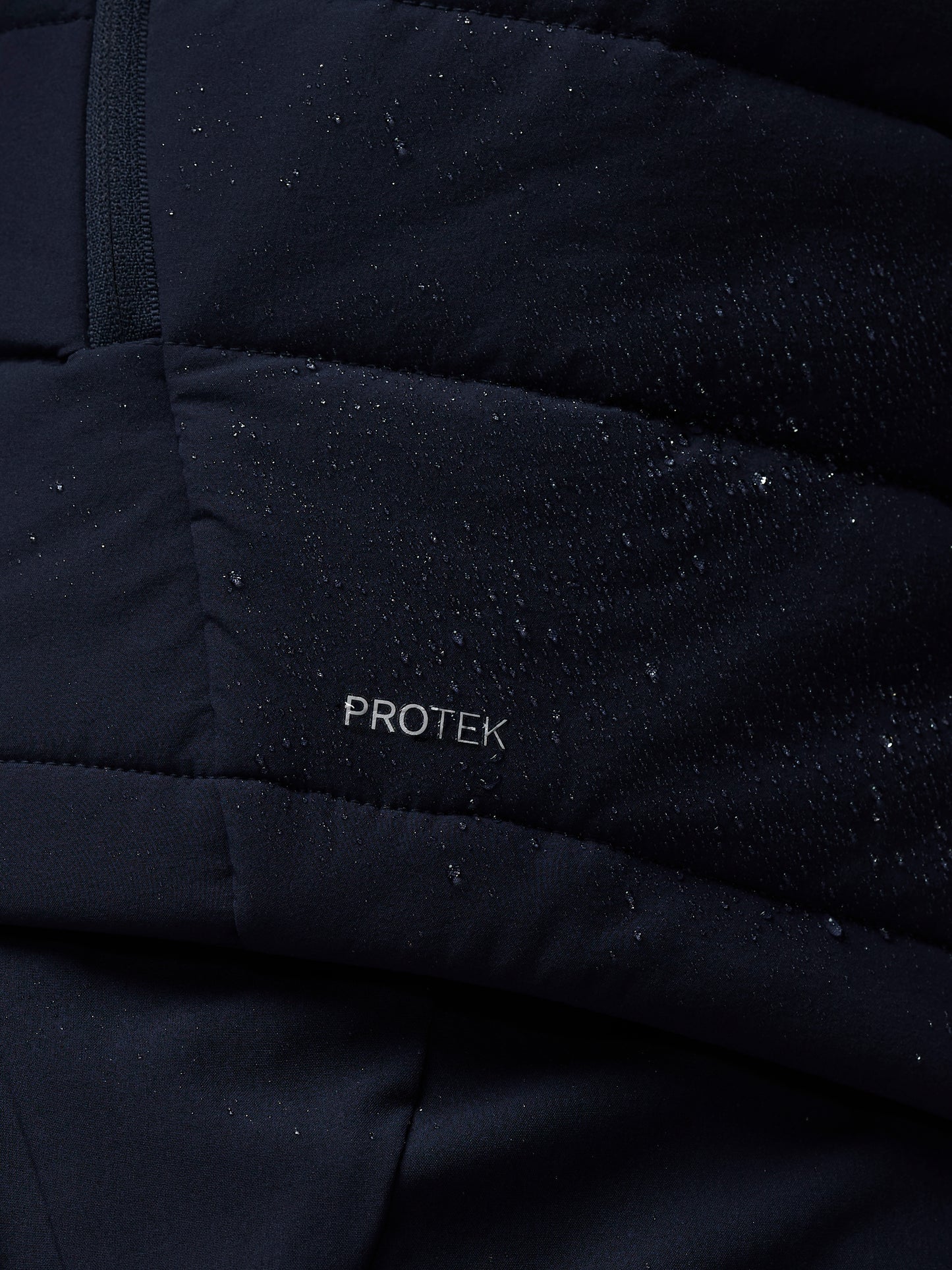 Close-up of a black quilted jacket with 'PROTEK' branding.