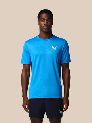 Man wearing a blue athletic shirt with a logo on a beige background