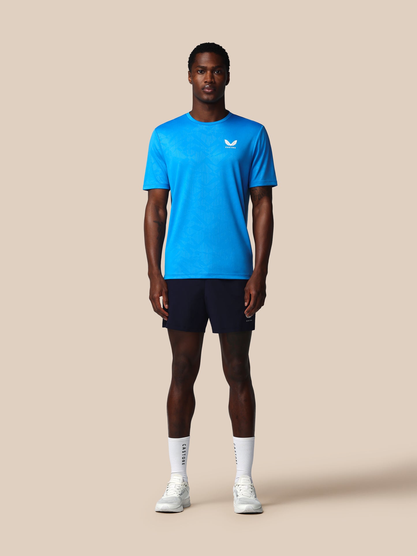 Person wearing a blue athletic shirt and black shorts on a beige background
