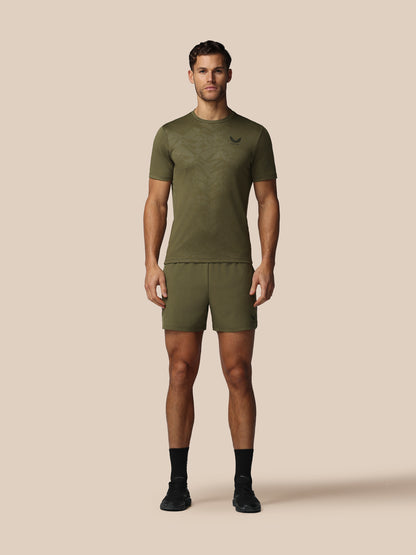 Man wearing an olive green athletic outfit on a beige background