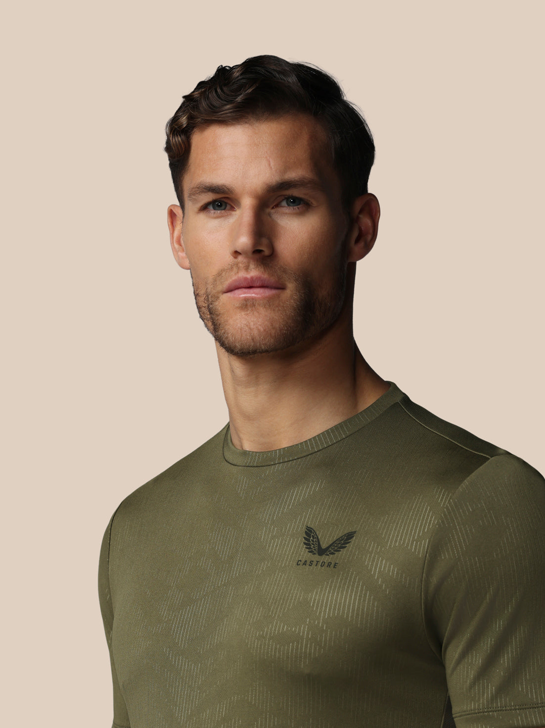 Man wearing a green athletic shirt with a logo on a beige background