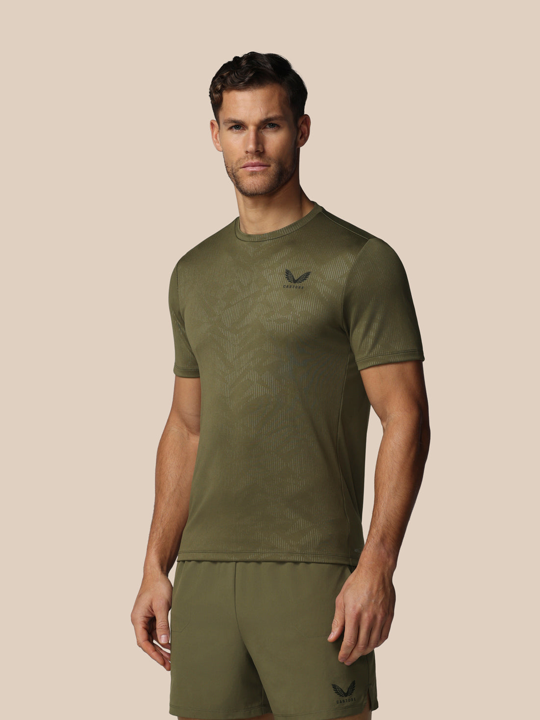 Man wearing a green athletic outfit with a logo on a beige background