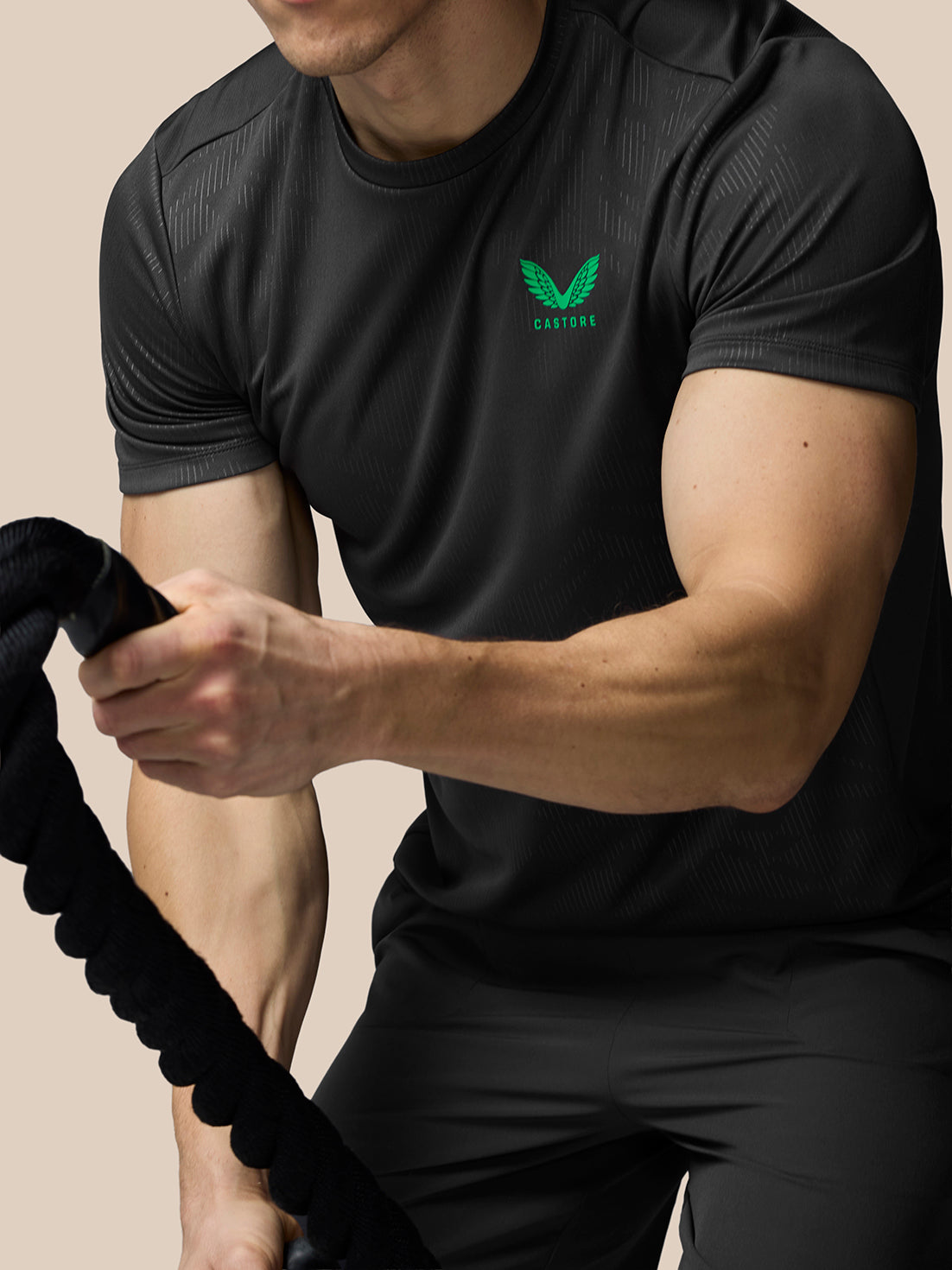 Person wearing a black athletic outfit with a green logo on a beige background