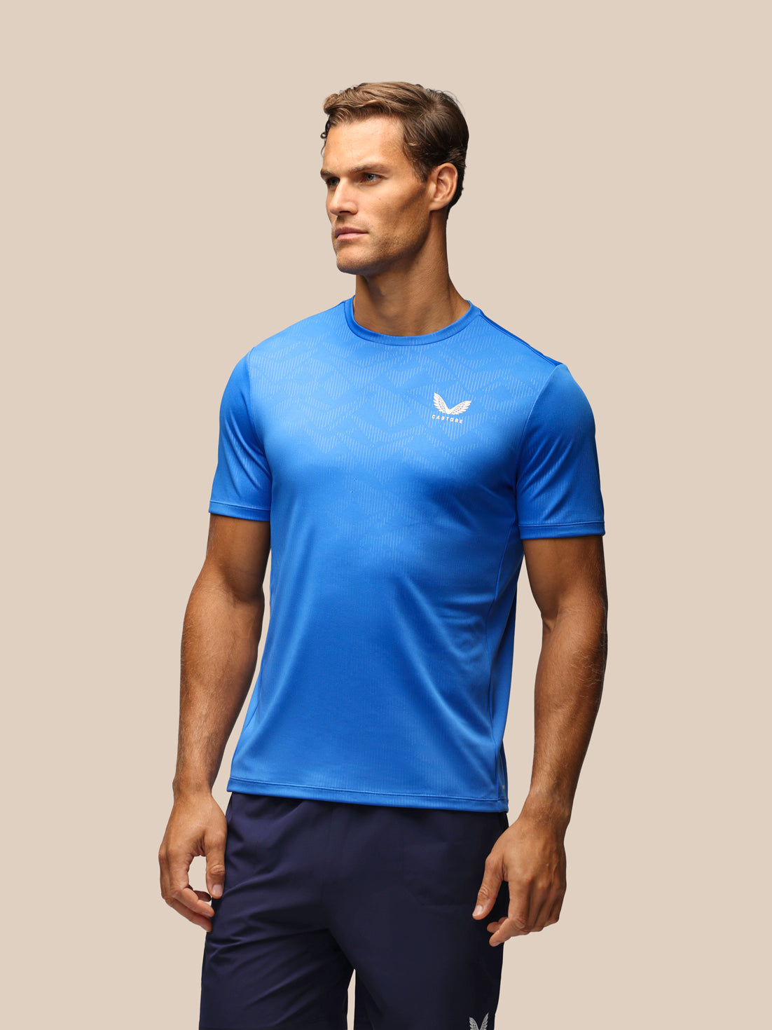Male model wearing a blue Adapt short sleeve tee with a subtle geometric print.