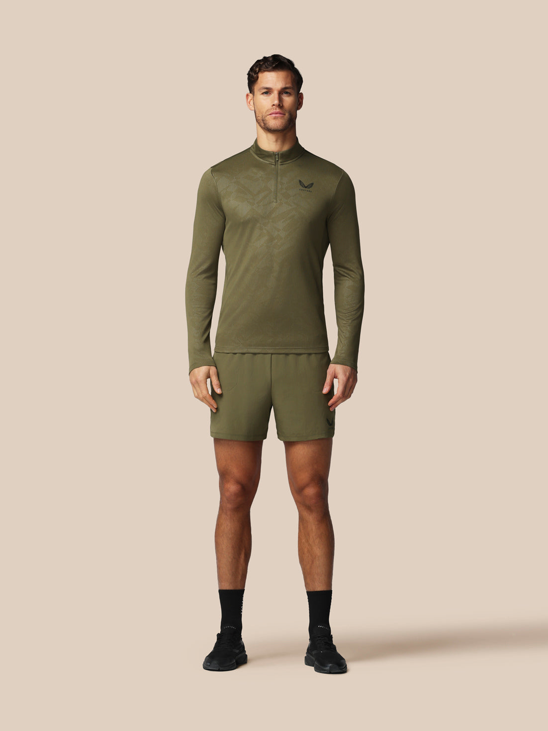 Man wearing a green athletic outfit with a brand logo on a beige background