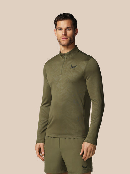 Man wearing a green athletic outfit with a logo on a beige background