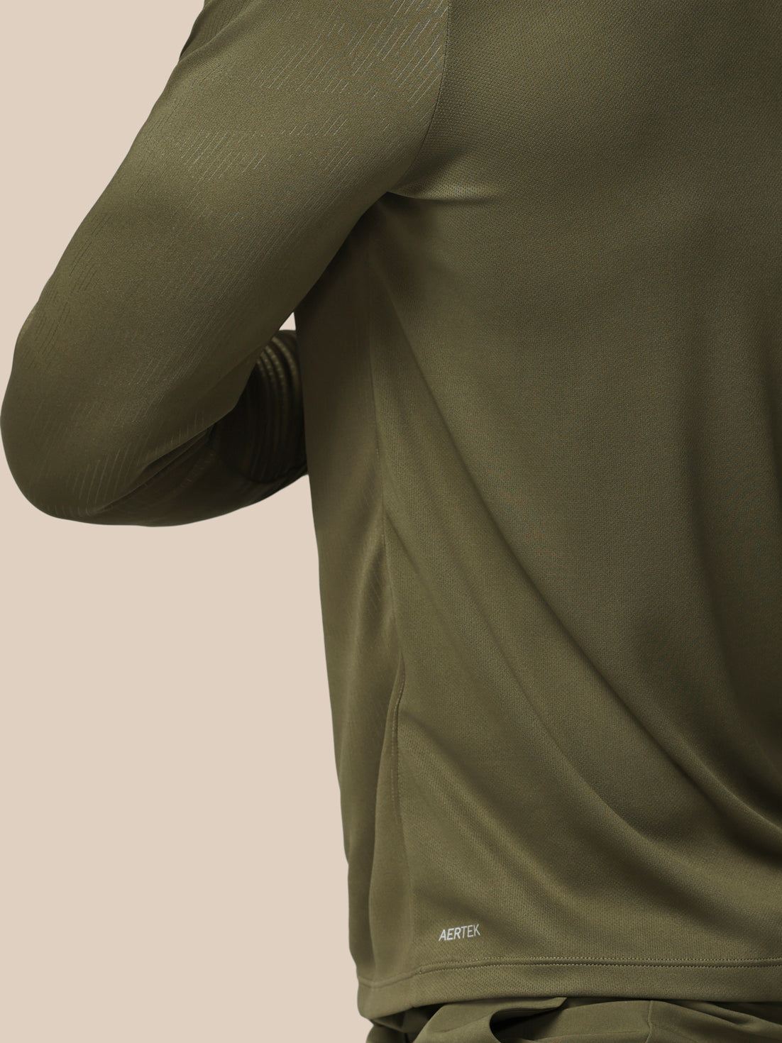 Person wearing a green athletic outfit with a brand logo on a beige background