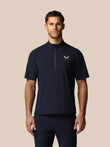 Man wearing a navy blue athletic shirt with Castore logo on a beige background