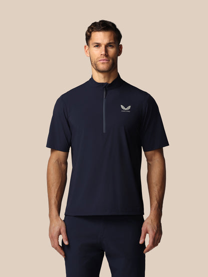 Man wearing a navy blue athletic shirt with Castore logo on a beige background