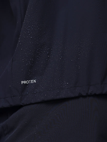 Close-up of a navy jacket with 'PROTEK' branding on a dark background