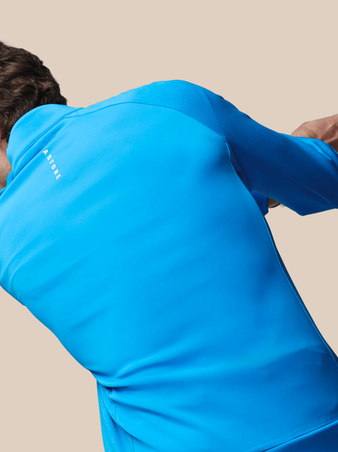 Person wearing a blue hoodie with Castore wordmark on a beige background