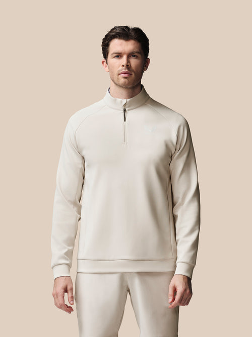 Man wearing a cream-colored outfit against a beige background