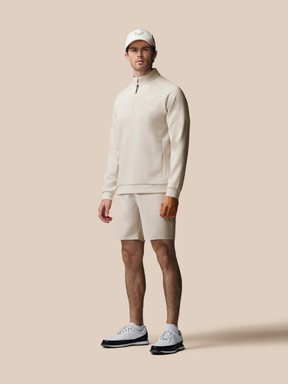 Man wearing a beige outfit with a cap on a beige background