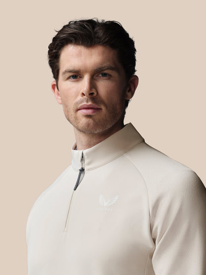 Man wearing a beige half-zip sweatshirt against a beige background