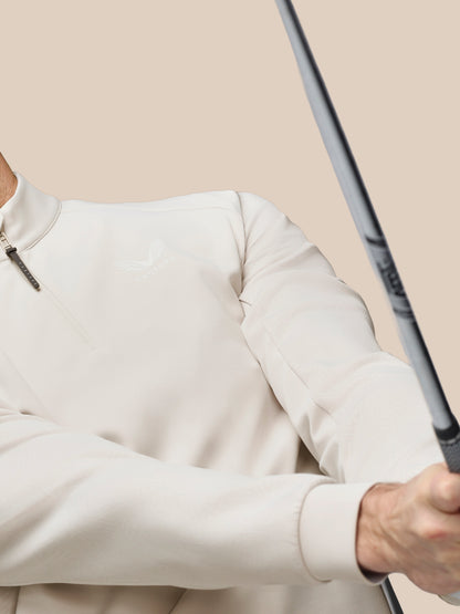 Person wearing a light gray sweatshirt holding a golf club against a beige background