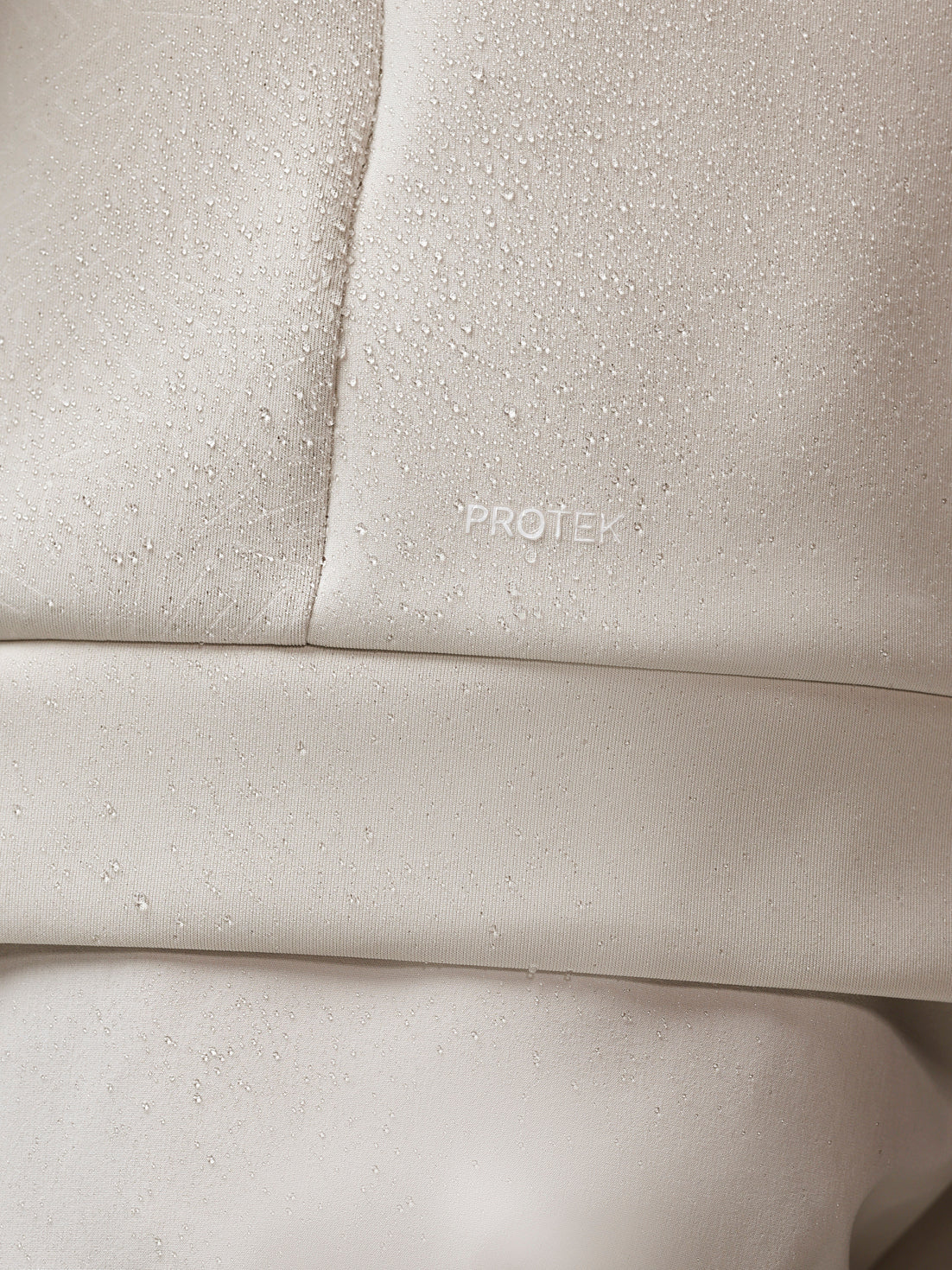 Close-up of beige fabric with 'PROTEK' branding.