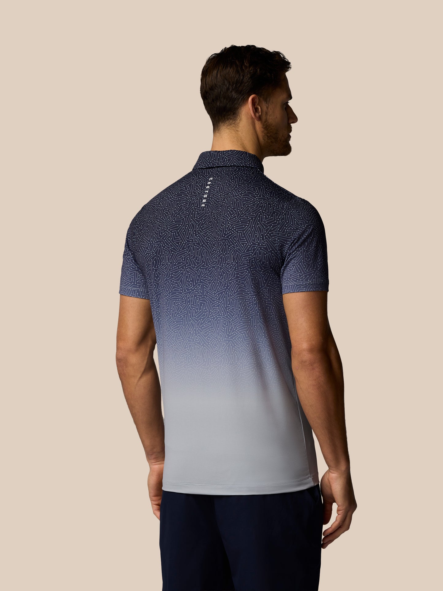 Man wearing a blue and gray gradient polo shirt on a beige background